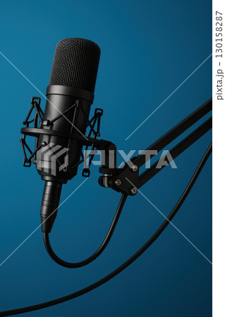 Professional studio microphone with shock mount and adjustable arm setup for podcasting and broadcasting, isolated on blue background with clear focus and high resolution Professional studio microphone with shock mount and adjustable arm setup for podcasting and broadcasting, isolated on blue background with clear focus and high resolution 130158287