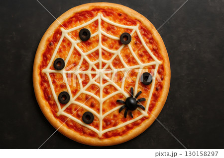 Spider web pizza with black olives and string cheese on festive Halloween food art design, overhead view of creative spooky meal for celebration 130158297