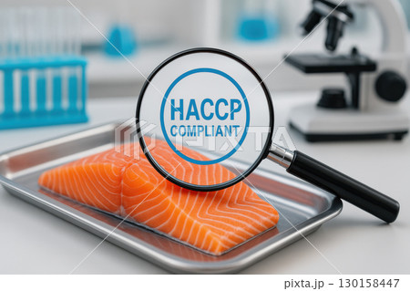 Fresh salmon fillet on stainless steel tray with magnifying glass highlighting HACCP compliance in modern seafood laboratory, emphasizing high quality and food safety standards 130158447