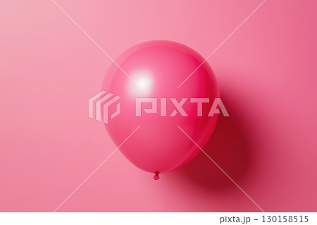 Pink balloon floating gently against a vibrant pink background, creating a cheerful and playful atmosphere 130158515