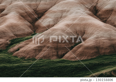 Unique landscape features with rolling hills and green vegetation during daylight 130158806