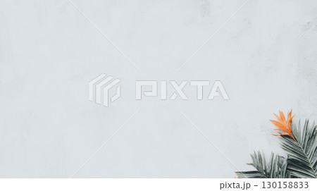 Tropical leaf arrangement with vibrant orange flower against a soft pastel background in an artistic setting 130158833