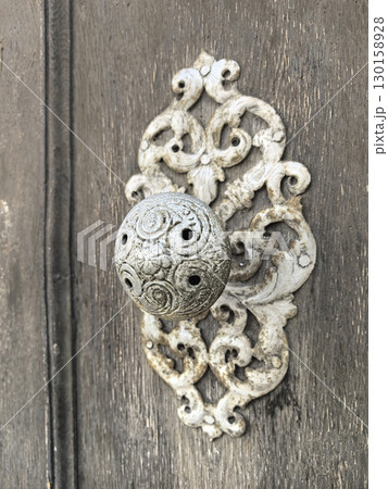 Intricate decorative door handle adds charm to rustic wooden entrance Intricate decorative door handle adds charm to rustic wooden entrance 130158928