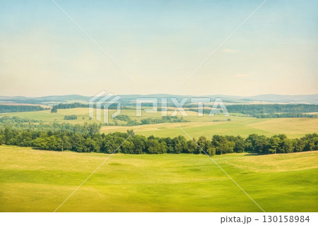 Vast green landscape with rolling hills and clear blue sky in a serene countryside setting 130158984