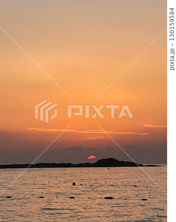 Sunrise over the sea with small island silhouette, golden sky and sun reflection on water, tranquil seascape at dawn Sunrise over the sea with small island silhouette, golden sky and sun reflection on water, tranquil seascape at dawn 130159584