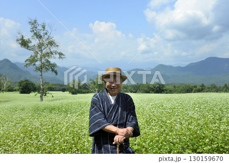 杖を使用してソバ畑を散策している老人 130159670