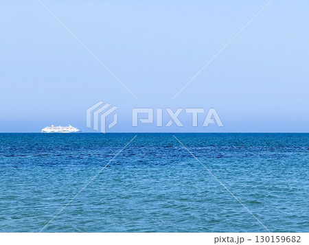 Picturesque beach, waves crashing on the sandy shore. Sea waves beat against the rocks. Cyprus Island, umbrellas, tourist boats, Mediterranean Sea. 130159682