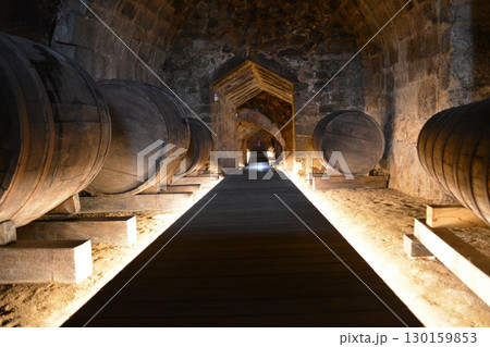 A historic wine cellar with an antique wooden press, grape crusher, and giant barrel. The concept is traditional winemaking heritage and craftsmanship. 130159853