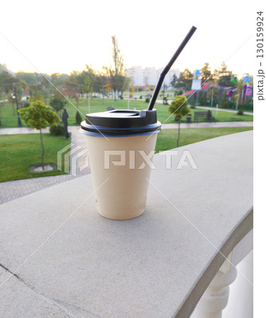 disposable cup with a hot drink in hand, in a city park 130159924
