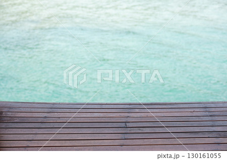 Wooden deck overlooking calm turquoise water for relaxation and leisure Wooden deck overlooking calm turquoise water for relaxation and leisure 130161055