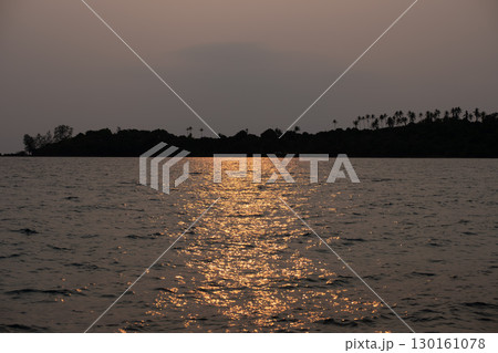 Sunset reflecting on ocean water near silhouetted island with palm trees Sunset reflecting on ocean water near silhouetted island with palm trees 130161078