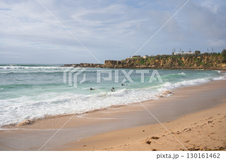 Surfers floating on ocean waves on calm beach 130161462
