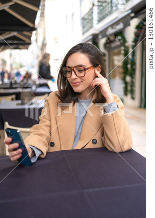 Middle-aged woman using smartphone sitting outdoor 130161466