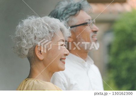 自宅の庭を眺めるシニア夫婦 130162300
