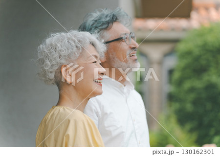 自宅の庭を眺めるシニア夫婦 130162301