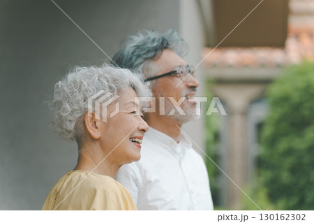 自宅の庭を眺めるシニア夫婦 130162302