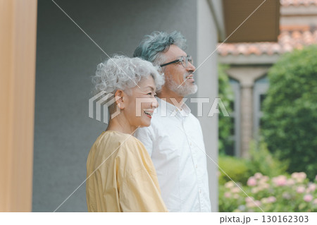 自宅の庭を眺めるシニア夫婦 130162303