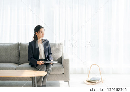 リビングのソファに座るスーツの女性 リビングのソファに座るスーツの女性 130162543