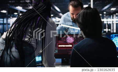 Technicians in AI server hub panicked by hacking attempt stealing sensitive company data. Team of data center IT experts fighting computer virus triggered by security systems, camera A 130162635
