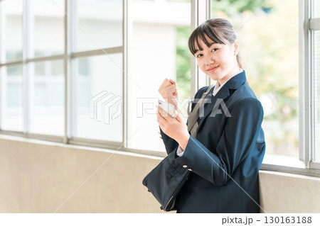 校舎の廊下でスマホを使う笑顔の小学生,中学生,高校生の女の子(ガッツポーズ) 校舎の廊下でスマホを使う笑顔の小学生,中学生,高校生の女の子(ガッツポーズ) 130163188