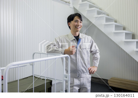 倉庫で台車を押す作業着の男性 130164011