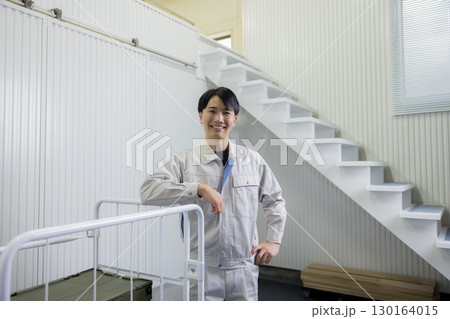 倉庫で台車を押す作業着の男性 130164015