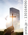 A holy bible, the cross of Jesus Christ, a dove, a brightly shining sun, and a sunset landscape background. 130164090
