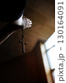 The hands of a Christian holding the cross of Jesus Christ in a church and praying with both hands together 130164091
