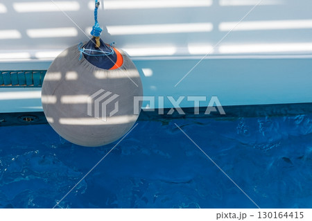 Boat fender hanging over blue water 130164415