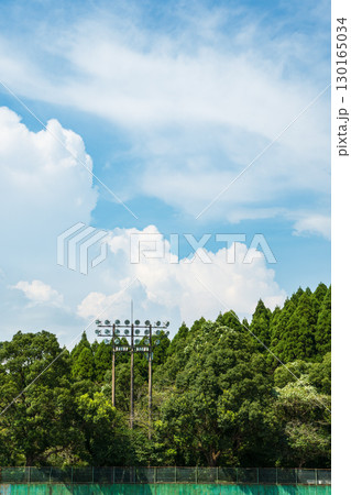 夏空に映える野球場の照明設備と豊かな森林の風景 130165034