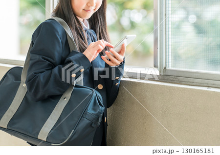 校舎の廊下でスマホを使う笑顔の小学生,中学生,高校生の女の子（防犯,安全,安心） 130165181