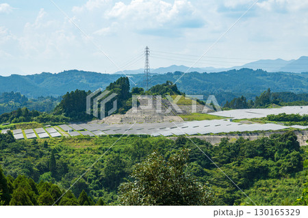 森林に囲まれた太陽光発電施設と送電線の景観 130165329