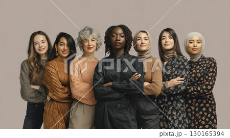 Diverse group of confident women standing together with arms crossed and smiling, showcasing unity and empowerment in neutral setting 130165394