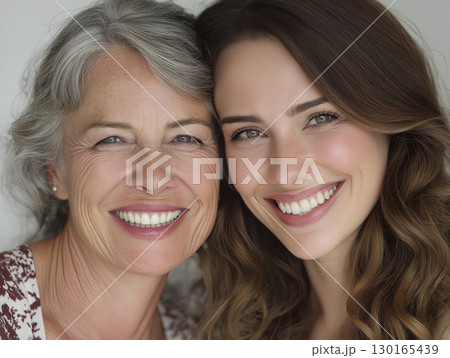 Close up of smiling mother and daughter with bright expressions, showcasing generational bond and happiness, capturing joyful family moment 130165439