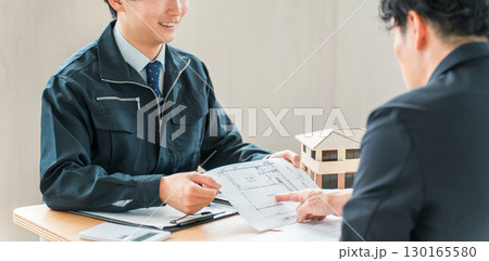 設計図を使い物件の説明をする作業着姿の営業マン,設計士の男性スタッフ 設計図を使い物件の説明をする作業着姿の営業マン,設計士の男性スタッフ 130165580