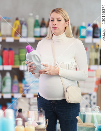 Pregnant woman choosing eco-friendly detergent in supermarket 130166374