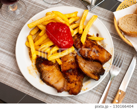 Roasted pork loin slices with fried potatoes and baked red pepper 130166404