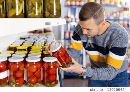 Portrait of man buying canned tomatoes at grocery store 130166424