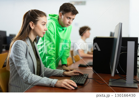 Female teacher explaining task solution to young boy Female teacher explaining task solution to young boy 130166430