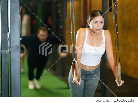 Sportive young girl working out with gymnastic rings in gym during crossfit workout Sportive young girl working out with gymnastic rings in gym during crossfit workout 130166535