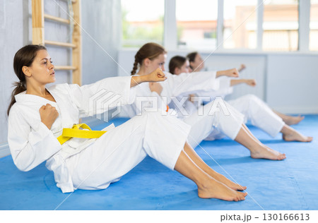 Girl athlete before martial match doing exercises to strengthen press and improve accuracy of hands 130166613