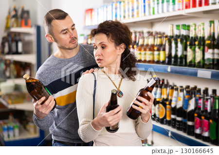 In Russian goods store, woman with husband choose bottle of beer In Russian goods store, woman with husband choose bottle of beer 130166645