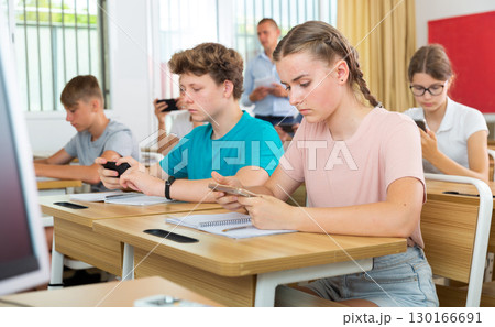 Teen students using smartphones on lecture in college class Teen students using smartphones on lecture in college class 130166691
