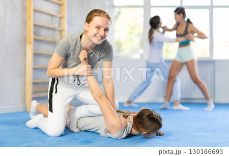 Concentrated girl practicing armlock in training bout during self-defence course 130166693