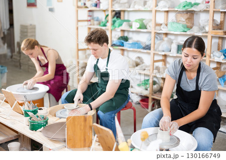 Young woman teacher and two teenagers make products on potter's wheel 130166749