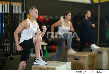 Focused man performing step-ups on box in functional training session Focused man performing step-ups on box in functional training session 130166786