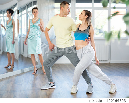 Woman and man in sportswear performing tango at dance rehearsal 130166868