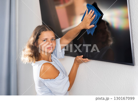Housewife wipes dust from the TV at home with rag 130167099