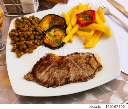 Beef steak with French fries, aubergine, peas and pesto 130167306