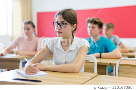 Portrait of positive teenage schoolgirl sitting on lesson 130167380